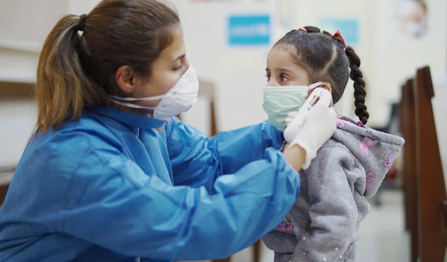 Women giving facemask to girl Women giving facemask to girl