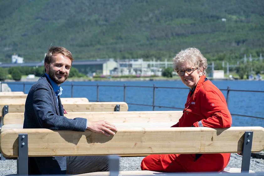 Vestre-sjef Jan Christian Vestre og Hydros konsernsjef Hilde Merete Aasheim på en benk laget av Hydro-aluminium. Hydros Husnes-anlegg i bakgrunnen. Vestre-sjef Jan Christian Vestre og Hydros konsernsjef Hilde Merete Aasheim på en benk laget av Hydro-aluminium. Hydros Husnes-anlegg i bakgrunnen.