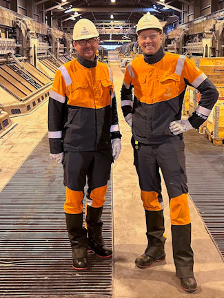 a couple of men in safety gear standing on a factory floor a couple of men in safety gear standing on a factory floor