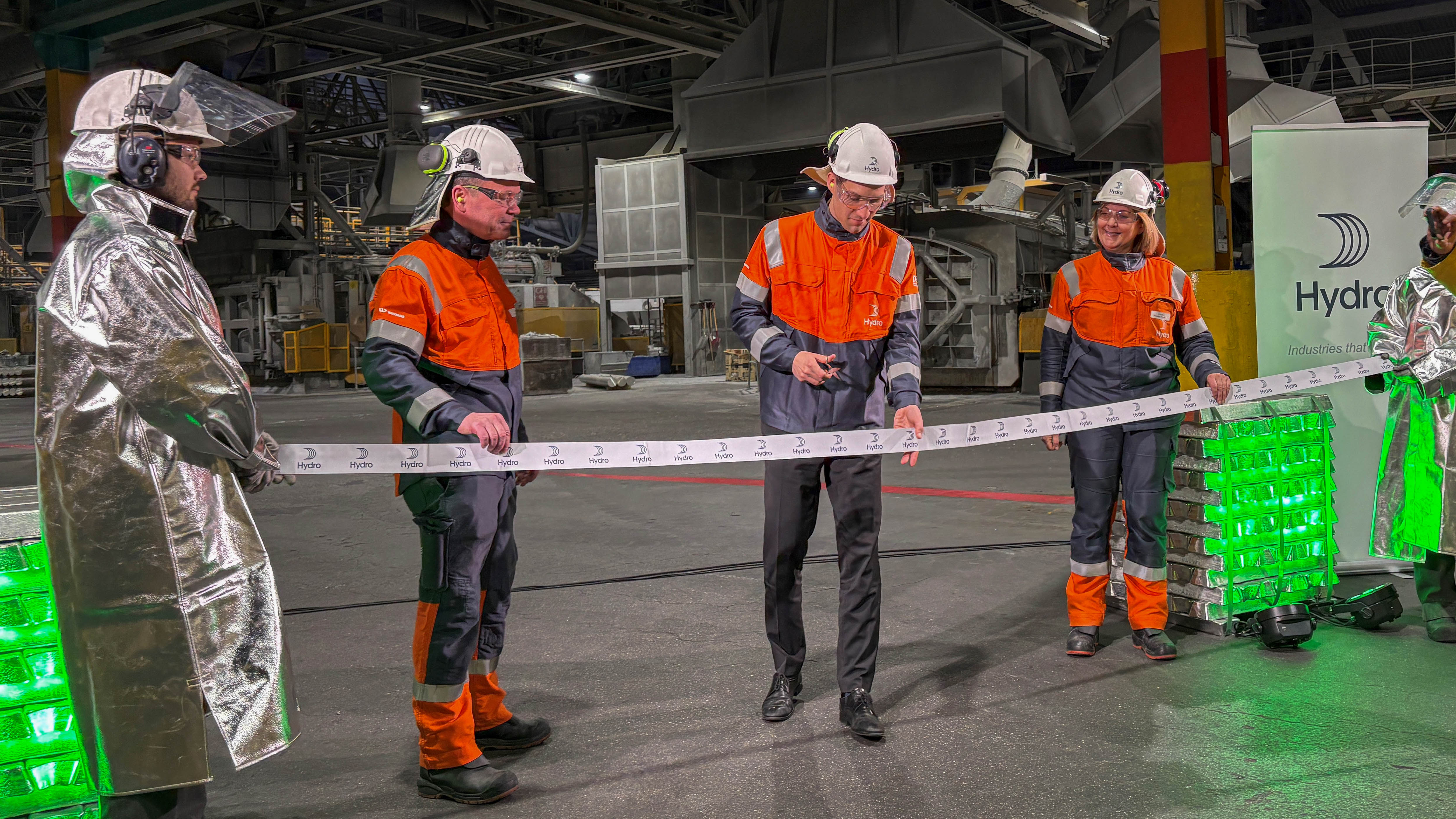 a group of people in safety gear holding a ribbon