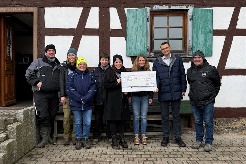 a group of people standing together holding a check