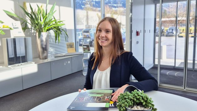 a woman sitting at a table with a plant and a book a woman sitting at a table with a plant and a book