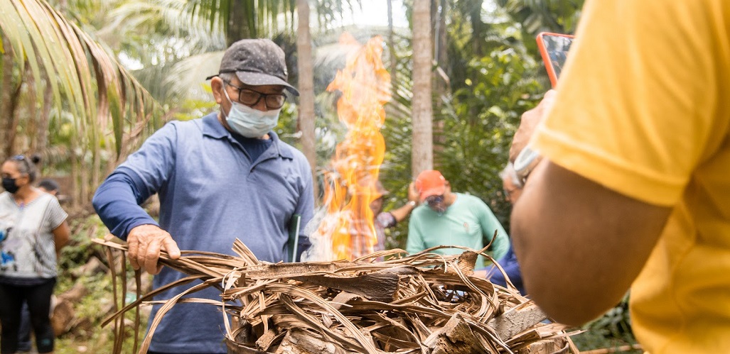 a person wearing a mask and holding a stick with fire in the background